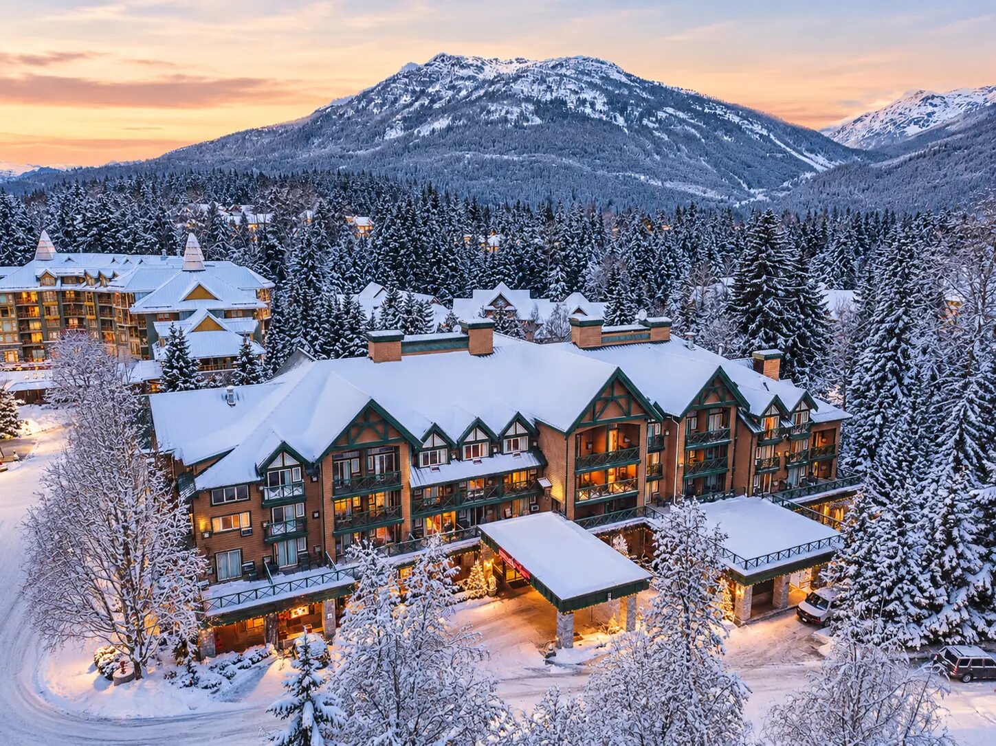 Pinnacle Hotel Whistler Village covered in snow at twilight, surrounded by mountains